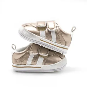 Detailed side view of stacked baby walking shoes in metallic gold with white stripes