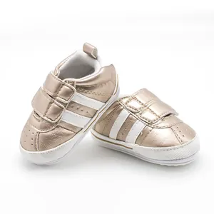 Detail view of metallic gold baby walker shoes with white stripes and velcro strap