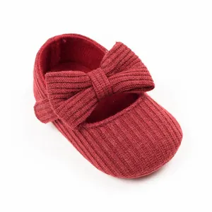 Macro view of burgundy knitted baby walker shoe featuring a large bow detail