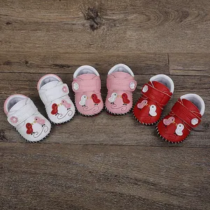 Detalle de tres pares de zapatos de gateo antideslizantes hechos a mano para bebés coloridos
