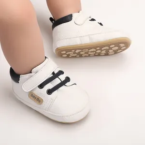 Close-up of white baby pre-walker shoes with navy trim and footprint pattern soft sole
