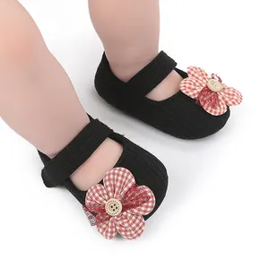 Detail of black baby soft sole walker shoes with a red gingham flower and wooden button.
