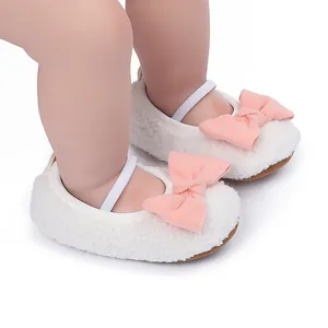 Vista detallada de zapatos de felpa blanca para bebés con un lazo rosa decorativo