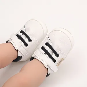 Detailed view of white baby pre-walker shoes with black laces and Baby Boy label