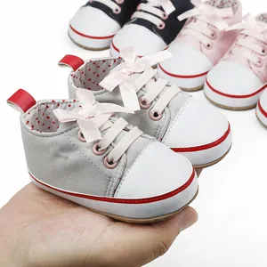 Close-up of grey infant walking shoes with soft sole and pink ribbon bow detail