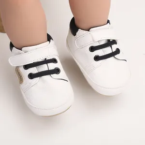Close-up detail of white baby casual walking shoes with black laces and Velcro strap