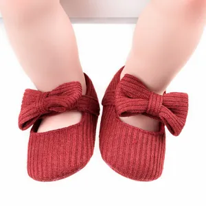 Detailed macro view of soft red ribbed knit baby shoes featuring a large decorative bow design