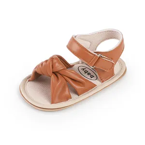 Detailed view of brown infant walking sandals featuring a soft knotted bow design