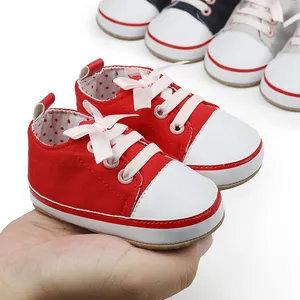 Close-up view of red canvas baby walker shoes with soft white soles and cute pink bows