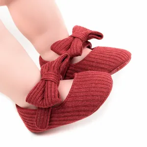 Close-up of red ribbed knit baby girl princess shoes with large bow decoration