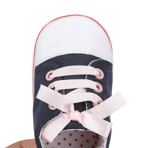 Close-up of baby pre-walker shoe with pink ribbon bow and navy canvas detail