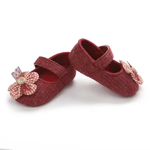 Primer plano de zapatos de princesa de punto rojo para bebé con flor de tela.