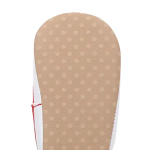 Close-up view of a baby walking shoe sole with anti-slip rubber dots and red stitching