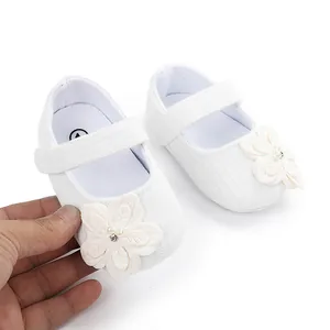 Dettaglio scarpine neonata bianche con suola morbida e decorazione floreale 3D elegante.