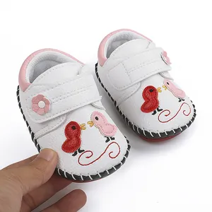 Primer plano de zapatos de bebé blancos con bordado de pájaros y cierre de velcro