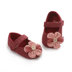Primer plano de zapatos de bebé rojos estilo princesa con adorno de flor y botón.