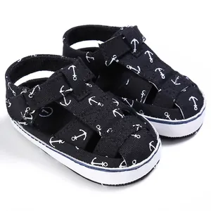 Close-up of black baby walking sandals with white anchor print and velcro strap