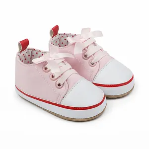 Detail of pink baby walking shoes with satin bow and white faux leather toe cap.