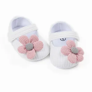Close-up of white knit baby princess shoes with soft pink fabric flower detail