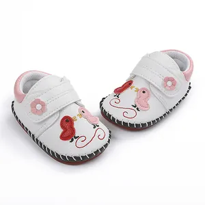 Vista detallada de zapatos de bebé cosidos a mano con diseño de pájaros de dibujos.