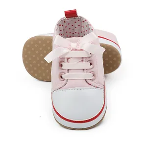 Close-up of pink infant girl walker shoes with a cute ribbon bow and polka dot lining
