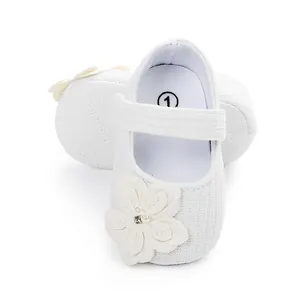 Dettaglio macro di scarpe da neonato bianche con suola morbida e un elegante fiore sulla punta.