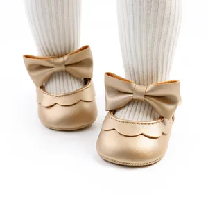 Close-up detail of golden baby princess shoes with a soft bow and scalloped edges
