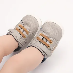 Macro view of soft grey faux leather infant pre-walker shoes with brown laces