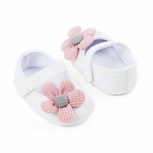 Close-up detail of white knitted baby shoes with pink flower decoration for infants