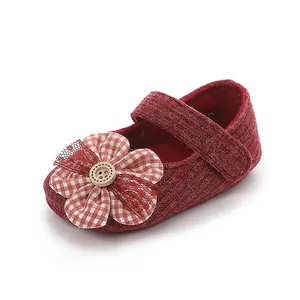 Primer plano detallado de un zapato de bebé rojo con aplique de flor y detalle de botón