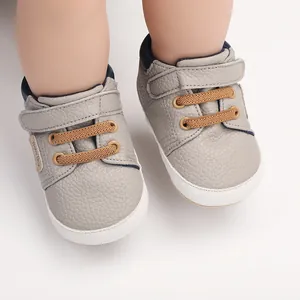 Detailed macro shot of grey leather baby pre-walker shoes with brown laces and white soles