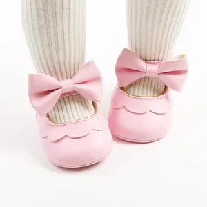 Detail shot of pink PU soft sole baby princess shoes with a large bowknot decoration.