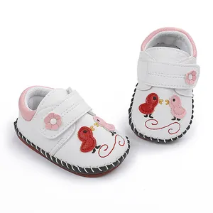 Detalle de zapatos para bebé cosidos a mano con bordado de pájaros y detalles en rosa