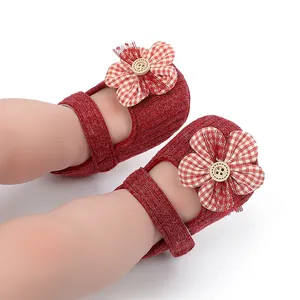 Detalle de zapatos de punto rojos para bebé niña con flor de cuadros y botón de madera natural