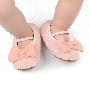 Primer plano de zapatos para bebé en forro polar rosa con lazo grande y suelas suaves