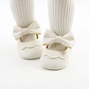 Close-up of elegant white baby princess shoes featuring a large PU bow and soft sole