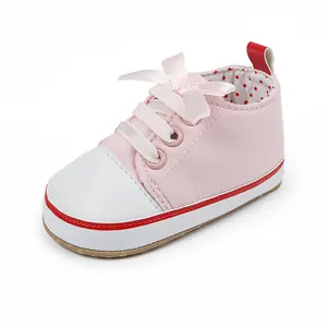 Close-up of pink baby girl pre-walker shoes with ribbon bow and polka dot lining
