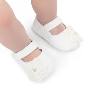 Dettaglio di eleganti scarpe da principessa bianche per neonato con fiori e perle