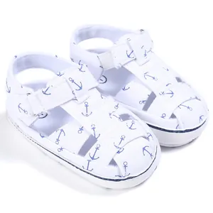 Detailed view of soft white baby sandals with blue anchor prints and velcro