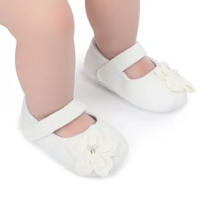 Dettaglio di scarpe da principessa bianche per neonati con decorazione floreale delicata
