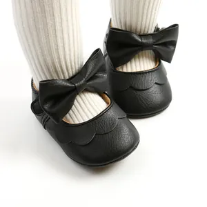 Macro detail of black PU leather baby walking shoes featuring cute bows and scalloped edges