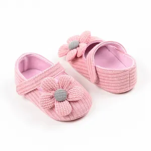 Close-up of pink knitted baby pre-walker shoes with a large 3D flower detail