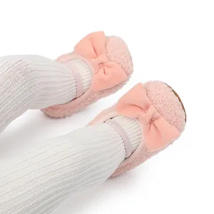 Primer plano de zapatos rosas de peluche para bebé con lazo y mallas