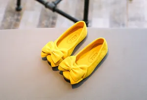 Detailansicht gelber Kinderschuhe mit einer großen dekorativen Schleife für Mädchen