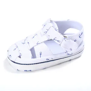 Close-up detail of white baby walker sandal with blue anchor patterns and velcro strap.