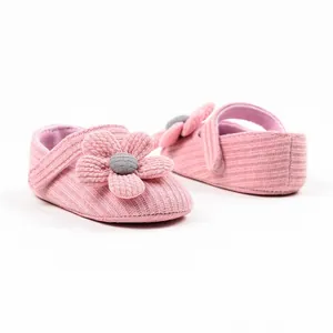 Detailed view of pink knitted baby shoes with large decorative flower applique