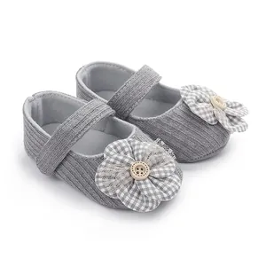 Detalle de zapatos de bebé para niña en punto gris con gran flor de tela y un botón.