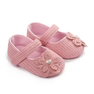 Vista dettagliata delle scarpine neonato rosa lavorate a maglia con fiore decorativo.