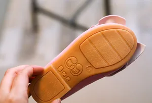Nahaufnahme einer rosa Kinderschuh-Gummisohle mit rutschfester Textur und Größe 21.