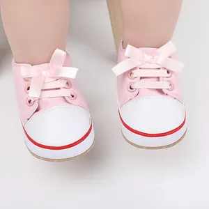 Close-up of pink infant walking shoes with ribbon bows and white toe caps